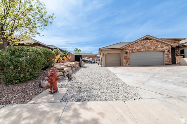 view of side of home featuring stone siding, a garage, stucco siding, and concrete driveway