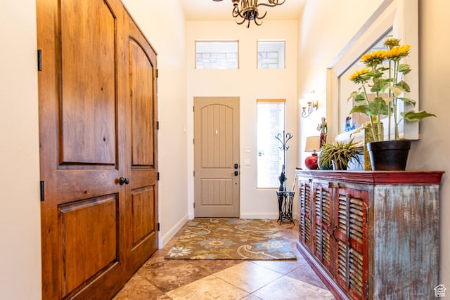 tiled foyer featuring baseboards and a chandelier