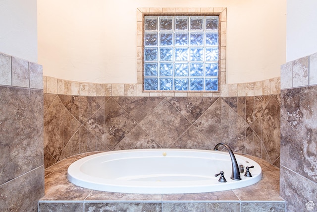 bathroom with tile walls, wainscoting, and a garden tub