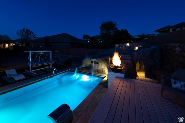 pool at night with an outdoor pool and a deck