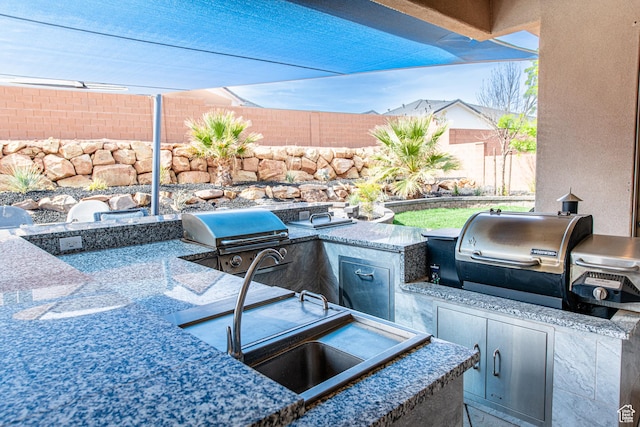 view of patio with exterior kitchen, a fenced backyard, a sink, and area for grilling