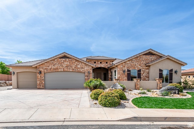 view of front of house with a tiled roof, stone siding, a garage, stucco siding, and driveway