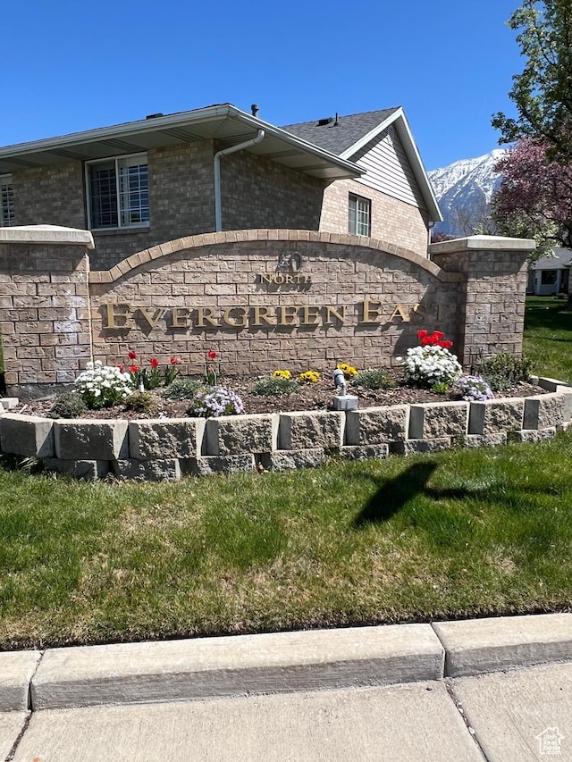 community sign with a mountain view and a lawn