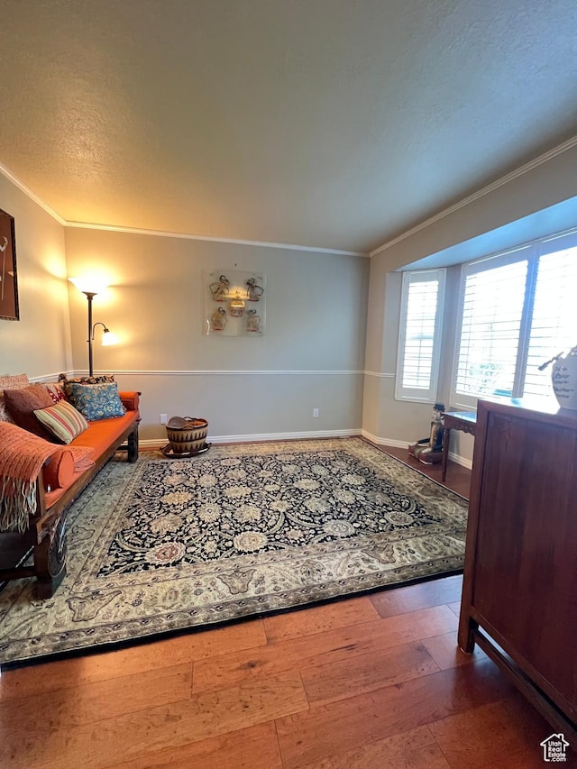 living room featuring crown molding, hardwood / wood-style floors, baseboards, and a textured ceiling