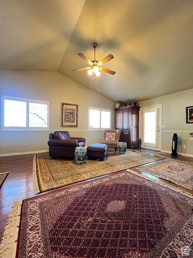 living room featuring wood finished floors, baseboards, a ceiling fan, and vaulted ceiling