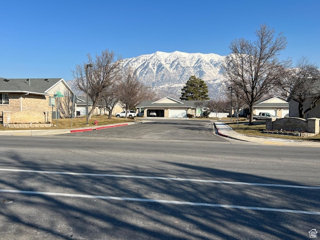 view of road with a residential view, a mountain view, street lights, curbs, and sidewalks