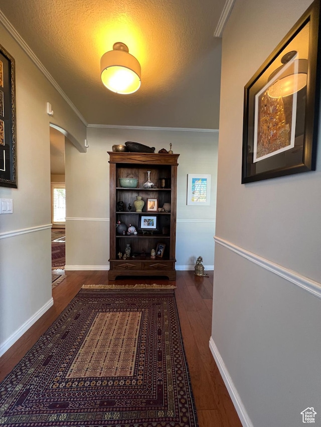 hallway featuring crown molding, arched walkways, hardwood / wood-style flooring, and a textured ceiling