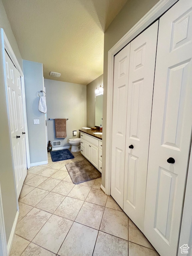 bathroom with visible vents, toilet, a textured ceiling, vanity, and tile patterned flooring