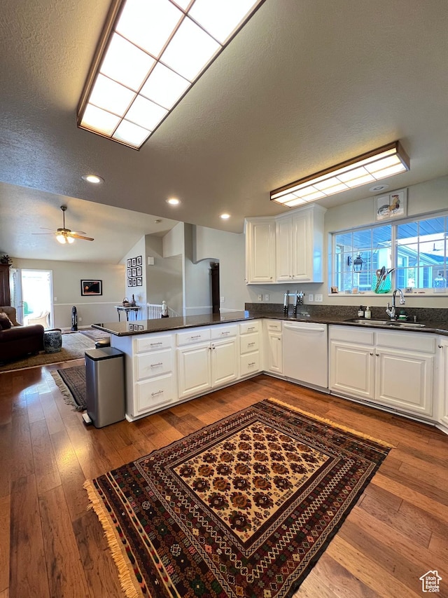 kitchen featuring white cabinetry, dishwasher, a sink, open floor plan, and hardwood / wood-style flooring
