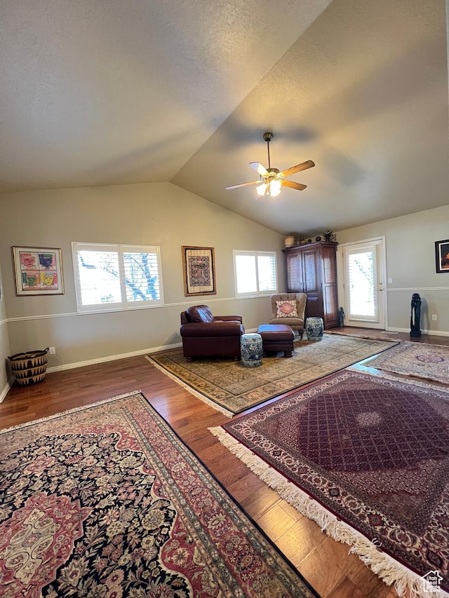 interior space featuring wood finished floors, baseboards, a ceiling fan, and vaulted ceiling