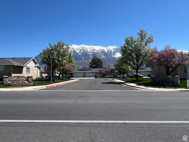 view of road featuring a mountain view, sidewalks, curbs, and a residential view