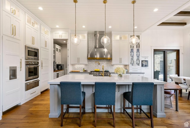kitchen with tasteful backsplash, dark wood-style flooring, a warming drawer, wall chimney exhaust hood, and stainless steel appliances