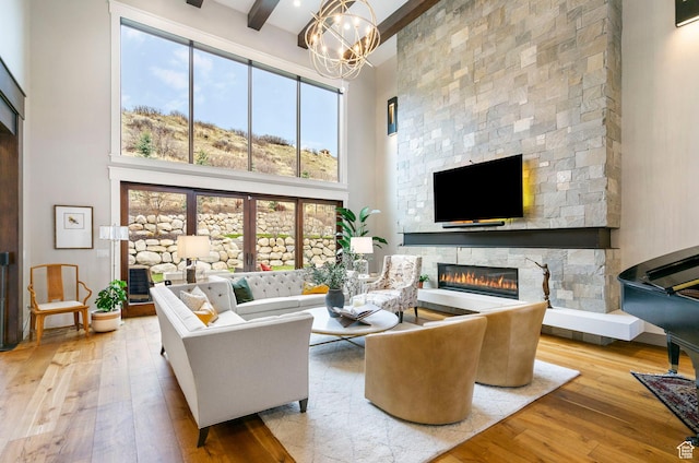 living area with an inviting chandelier, a high ceiling, a fireplace, beamed ceiling, and wood-type flooring