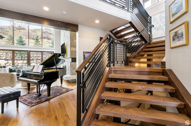 staircase featuring recessed lighting, a high ceiling, and hardwood / wood-style floors
