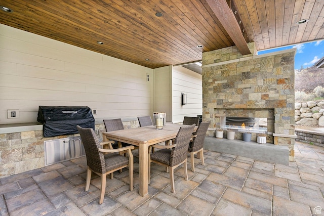 view of patio with outdoor dining area, an outdoor stone fireplace, and area for grilling