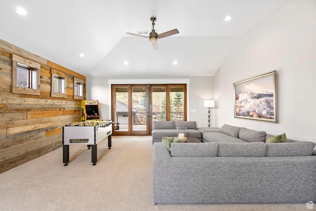 living room featuring vaulted ceiling, light carpet, recessed lighting, wooden walls, and a ceiling fan