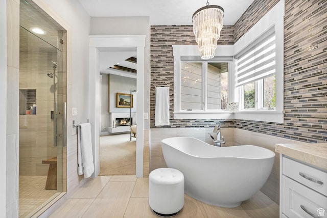 full bath featuring tile patterned floors, a freestanding tub, an inviting chandelier, and a stall shower