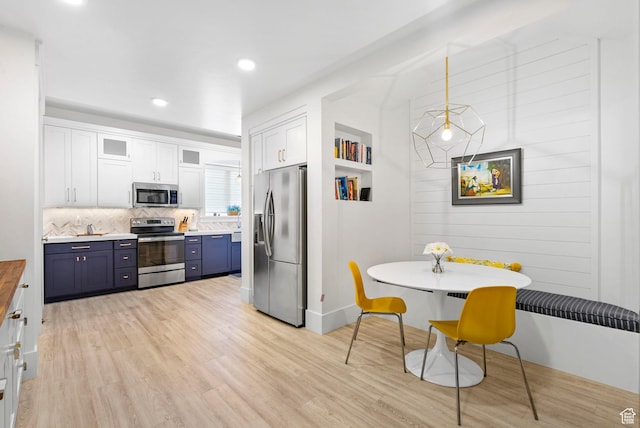 kitchen with light wood-style floors, white cabinets, appliances with stainless steel finishes, blue cabinets, and backsplash