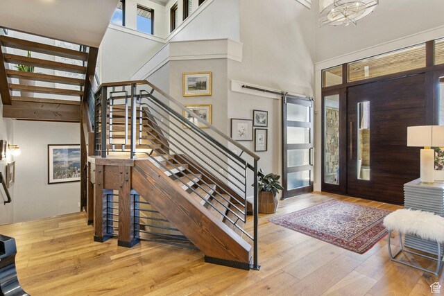 entryway featuring a barn door, stairway, a towering ceiling, and wood finished floors