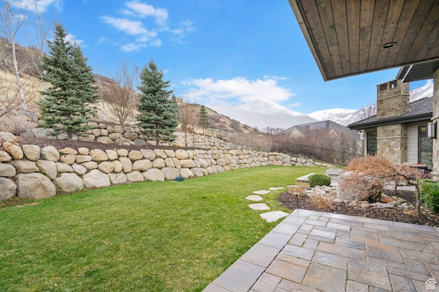 view of yard featuring a mountain view, fence, and a patio