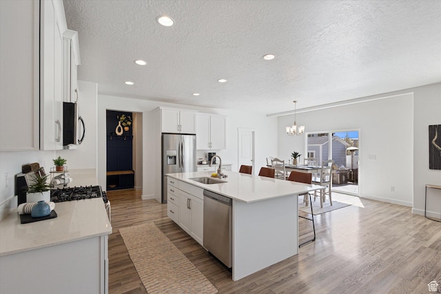 283 E Echo Ledge Dr S, Saratoga Springs, UT 84045 - kitchen with an inviting chandelier, light wood-style flooring, a textured ceiling, appliances with stainless steel finishes, and light countertops