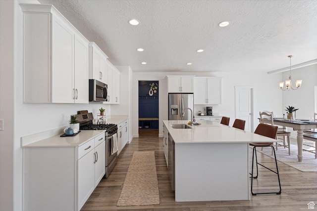 283 E Echo Ledge Dr S, Saratoga Springs, UT 84045 - kitchen with a textured ceiling, white cabinets, a kitchen bar, stainless steel appliances, and a sink