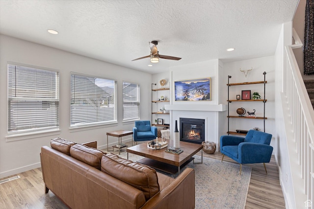 283 E Echo Ledge Dr S, Saratoga Springs, UT 84045 - living area featuring a glass covered fireplace, baseboards, light wood-style flooring, a ceiling fan, and visible vents