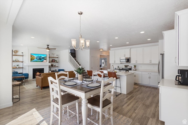 283 E Echo Ledge Dr S, Saratoga Springs, UT 84045 - dining area with recessed lighting, light wood finished floors, ceiling fan with notable chandelier, and a warm lit fireplace