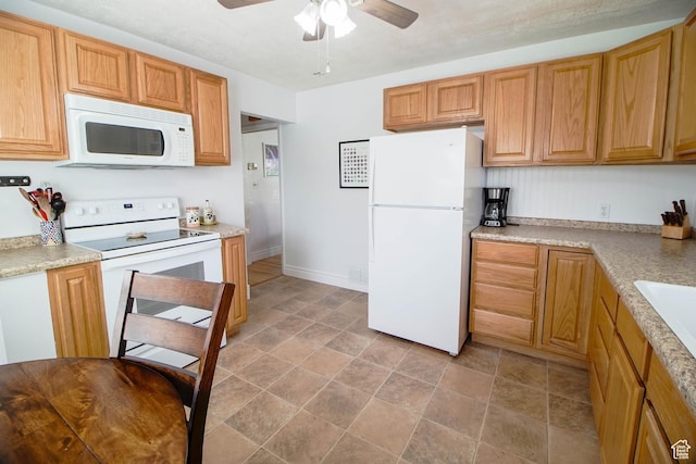 kitchen featuring a ceiling fan, light countertops, white appliances, and stone finish flooring