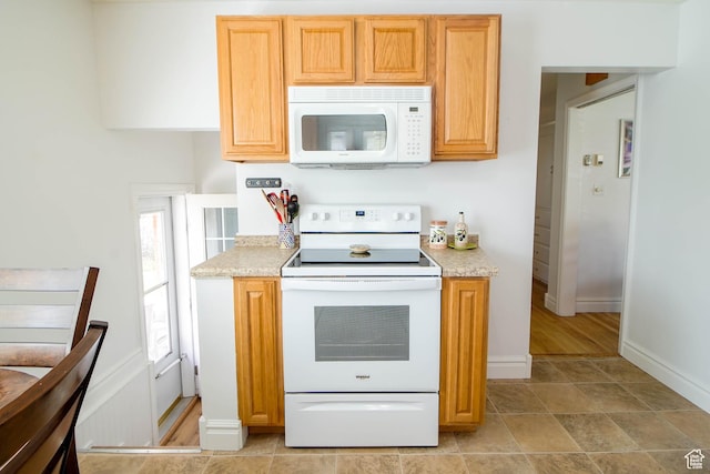 kitchen featuring baseboards and white appliances