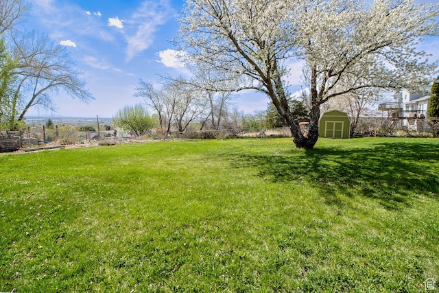 view of yard featuring a shed, an outdoor structure, and fence