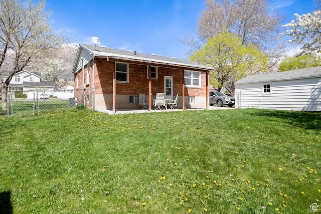 back of house with a yard, fence, brick siding, and a patio