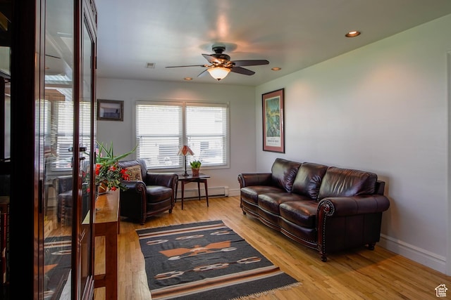 living room featuring ceiling fan, wood finished floors, a baseboard heating unit, and baseboards