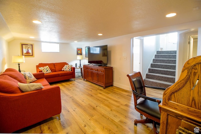living area with light wood-type flooring, recessed lighting, a textured ceiling, and stairway