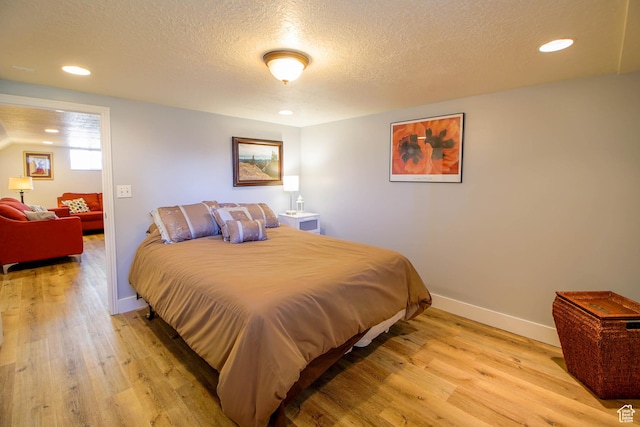 bedroom with baseboards, light wood finished floors, recessed lighting, and a textured ceiling