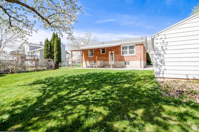 rear view of property featuring entry steps, a lawn, fence, a patio, and brick siding