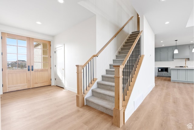foyer with light wood-type flooring, french doors, recessed lighting, and stairway