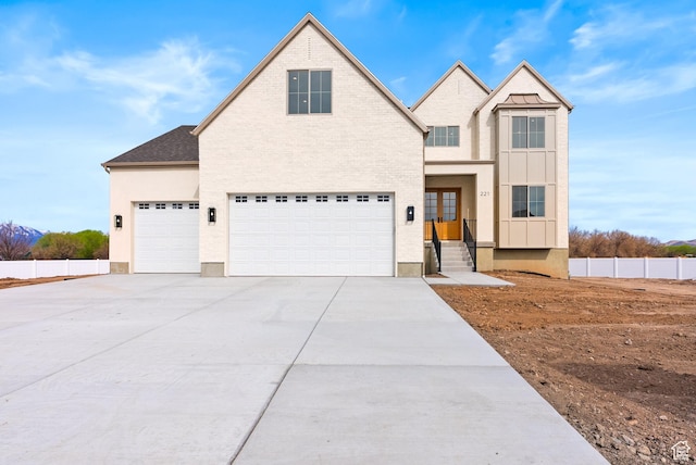 view of front of property featuring board and batten siding, an attached garage, fence, and driveway