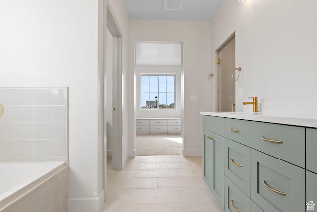 full bathroom with tile patterned floors, tiled tub, baseboards, and visible vents