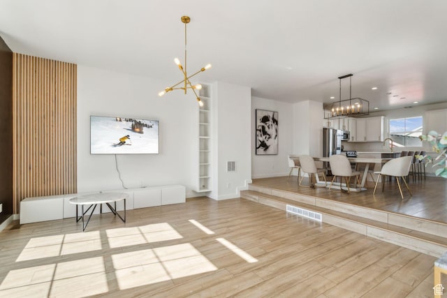 interior space featuring visible vents, baseboards, light wood finished floors, and a chandelier
