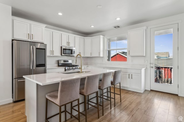 kitchen featuring light wood-style flooring, white cabinetry, a breakfast bar, and stainless steel appliances