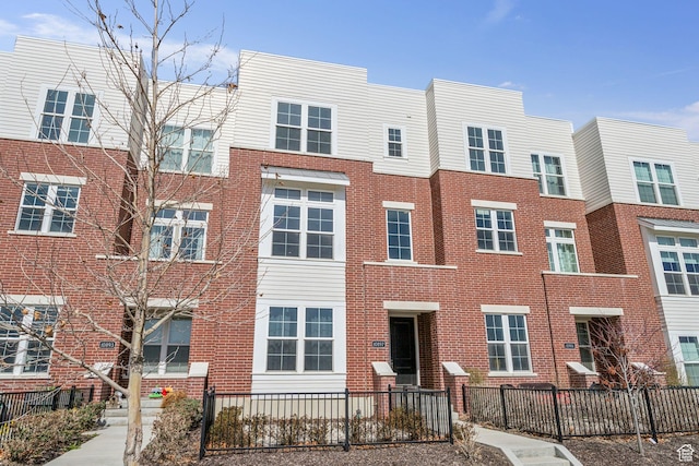 view of front facade featuring brick siding and fence