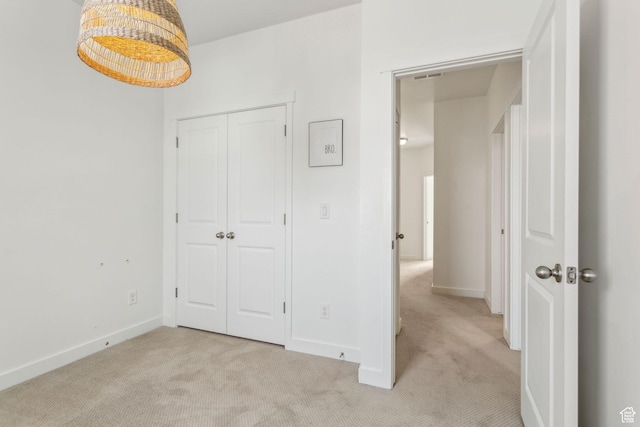 unfurnished bedroom featuring visible vents, a closet, baseboards, and light carpet