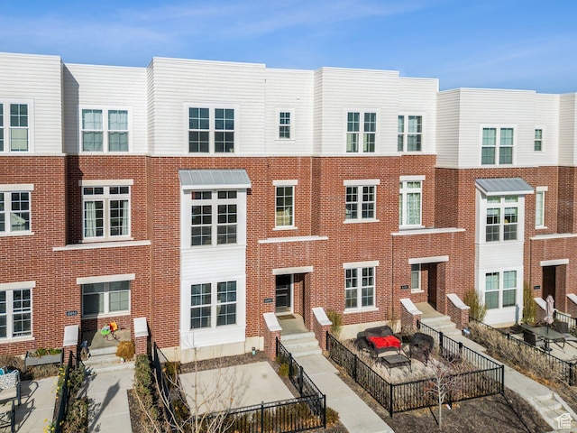 view of front of house featuring brick siding and fence