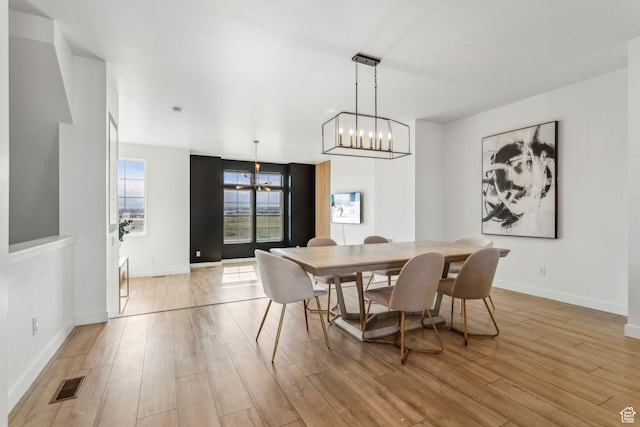 dining space featuring visible vents, baseboards, light wood-type flooring, and a notable chandelier