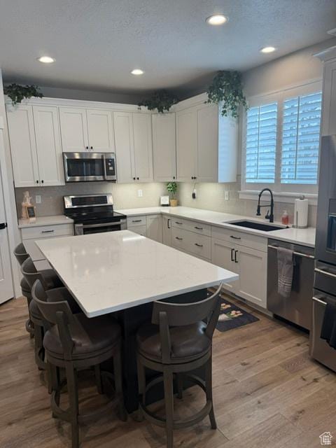 328 E 1100 S, Centerville, UT 84014 - kitchen with a kitchen breakfast bar, a kitchen island, appliances with stainless steel finishes, light countertops, and a sink