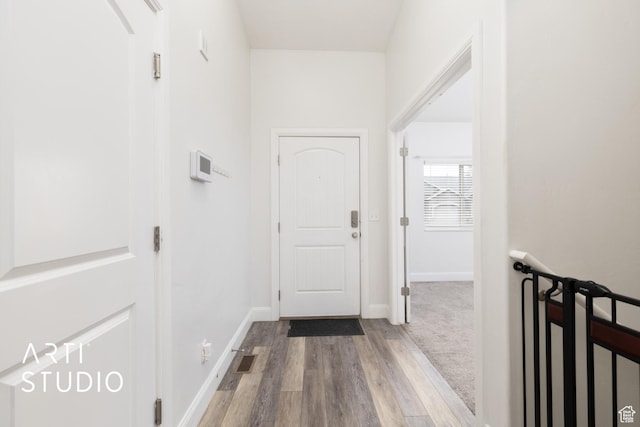 hallway featuring visible vents, baseboards, and wood finished floors