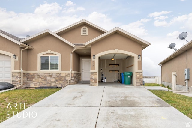 view of front of property with stucco siding, driveway, stone siding, a front yard, and a garage