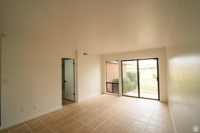 tiled spare room featuring visible vents and baseboards