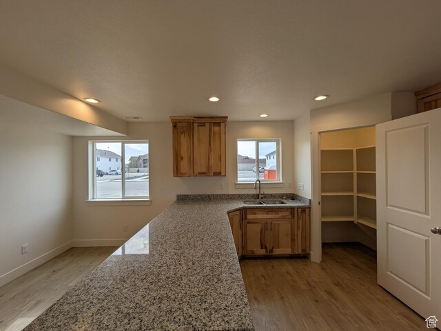 340 N 2650 W Unit 16, Tremonton, UT 84337 - kitchen featuring baseboards, a sink, brown cabinets, light wood finished floors, and light stone counters